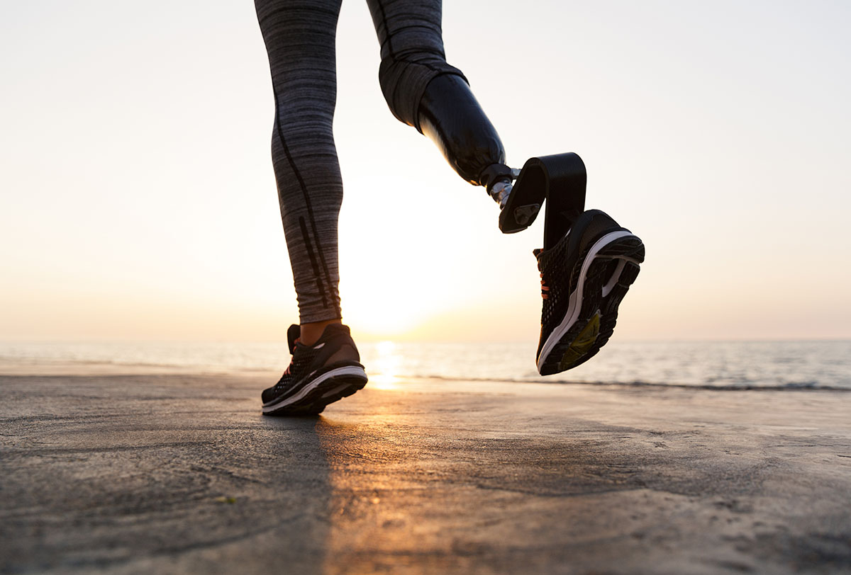 An athlete with a prosthetic leg running on a beach